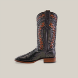 A single black Exotic Karoo Ostrich cowboy boot from the Herradura collection, featuring elaborate red-brown woven leather detailing and decorative stitching, highlighted by a wooden heel and pointed square toe against a plain light beige background.