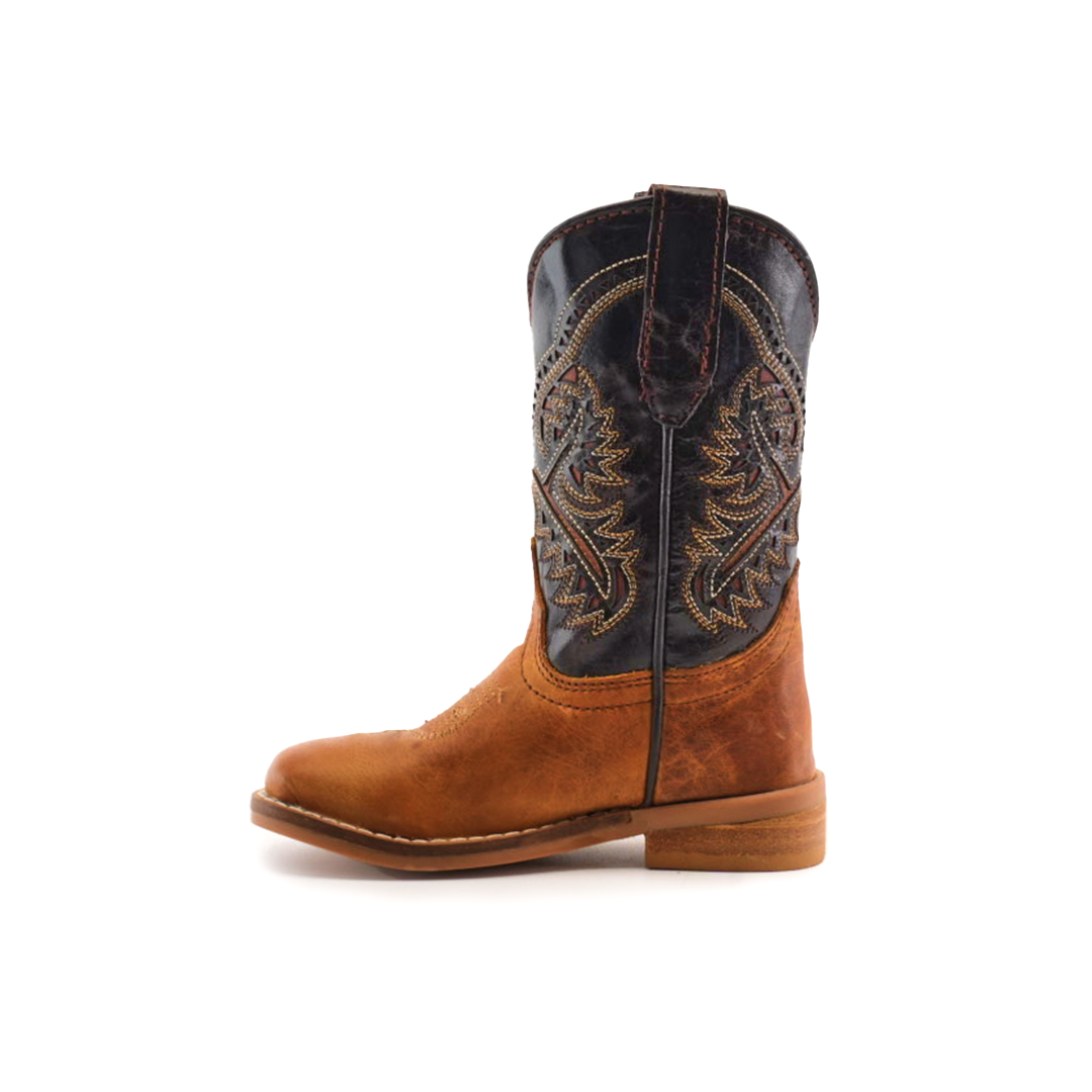 The Cater Honey Square Toe cowboy boot, crafted from cowhide leather, features a brown lower half and a dark upper shaft with intricate stitching. Its handcrafted design with a flat sole and almond-shaped toe exudes rustic elegance against a plain white background.