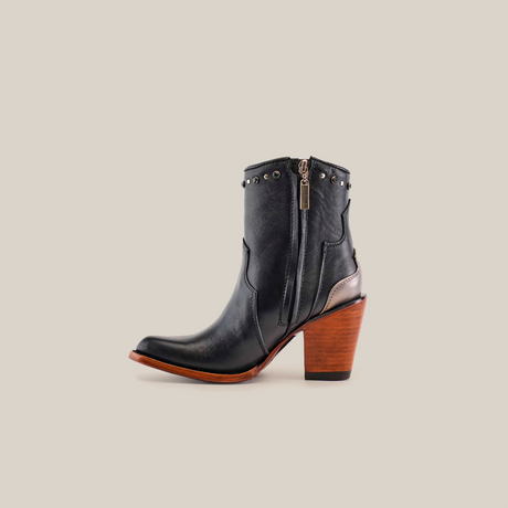 The Milan Chains Bootie Black - J Toe is a chic black ankle boot made from premium leather, highlighted by silver studs and chain accents. It sports a high brown wooden heel and toe, reflecting luxury craftsmanship against a plain white background.