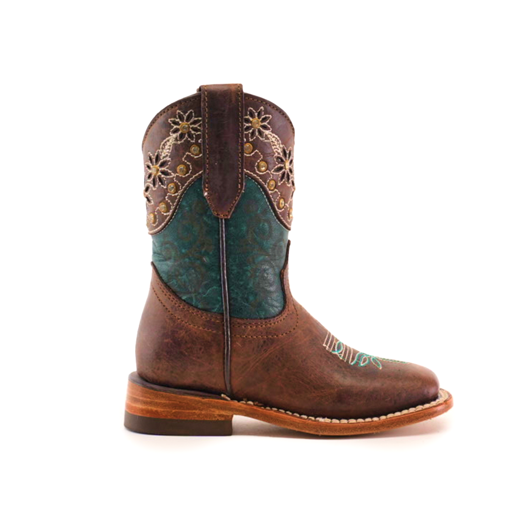 The Grecas Tabaco - Square Toe is a single brown cowboy boot featuring a decorative teal shaft with intricate floral embroidery. Made from premium leather, it has a low heel and rounded toe, showcasing detailed stitching on the vamp that reflects traditional craftsmanship.