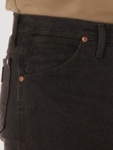 Close-up of someone wearing Wrangler Cowboy Cut Slim Fit Jean - 0936KCL in dark green with copper rivets, featuring a front pocket and belt loop. A brown shirt is neatly tucked in.