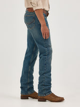 Dressed in Wrangler Mens 20X Extreme Relaxed Fit Jeans - 1044MWXMA with a beige shirt and brown woven shoes, a person stands sideways, arms at their sides. The premium denim jeans boast a classic fit with visible back pockets, while a belt peeks out against the plain light background.