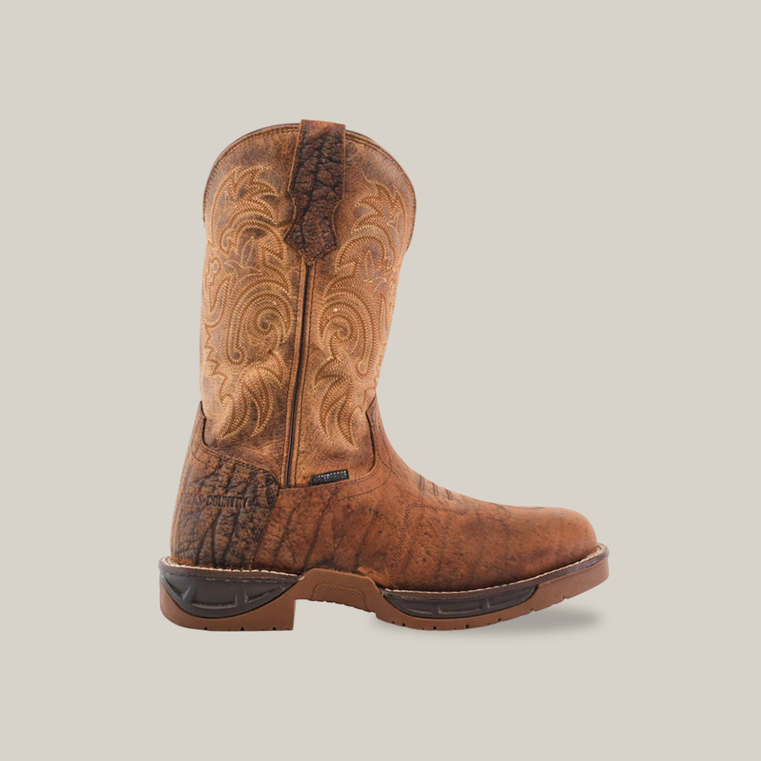 The Tan Brown Rough out boot features premium cowhide with ornate stitching, a rugged sole, and side pull-tab. Its handcrafted design and weathered look contrast beautifully against a plain white background.