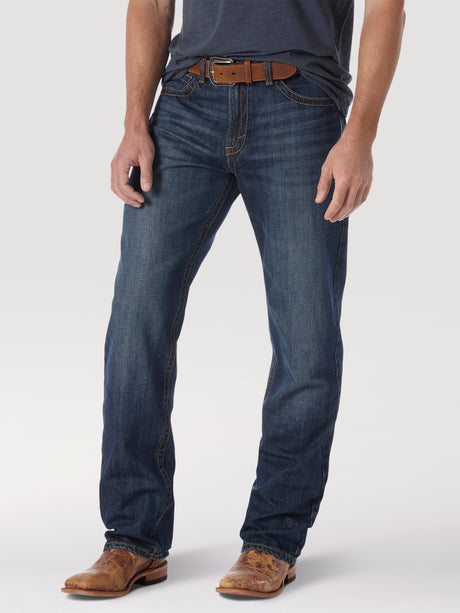 A person is wearing a black shirt and Wrangler® 20X® No. 33 Relaxed Straight Leg Jeans, finished with brown cowboy boots and a brown leather belt. The focus is on the lower body against a plain white background.