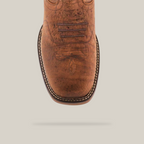 Close-up of the handcrafted Tan Brown Rough out - Waterproof - Composite Toe boot, made from premium cowhide leather. It features decorative stitching on the toe and a white stitched edge. The textured tan brown leather exudes rugged charm against a pristine white backdrop.