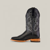 The Python Print Black - Square Toe is a black cowboy boot with intricate leaf patterns, woven texture on the lower part, and a chic snakeskin design. It features a square toe and rests on a brown wooden sole against a plain gray background.