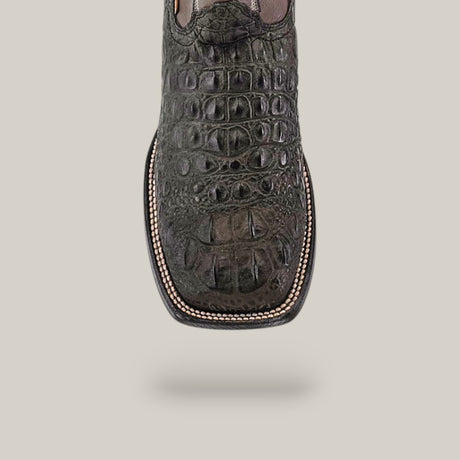 A close-up of the Alligatoar Head Print Gray shoe showcases its dark green crocodile leather, square toe, and intricate stitching. The alligator head print pops against a neutral background, creating a captivating textured design.