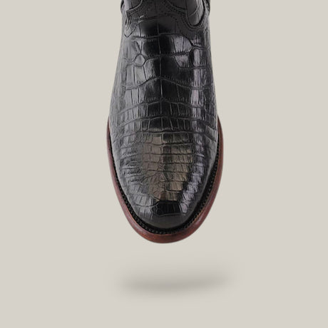 A black, glossy Exotic Full American Alligator shoe with a crocodile texture and brown sole is shown vertically against a plain, light gray background.