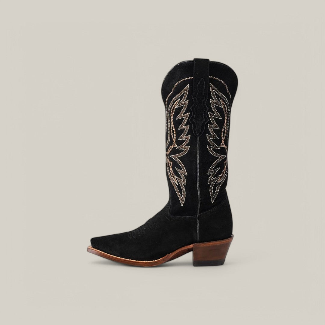 The Miranda Suede Black Leather Sole boot showcases intricate beige stitching on its mid shaft, a chic snip toe, and a wooden heel, all set against a plain gray background.