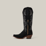 The Kellie Suede Black Leather Sole boot is showcased on a neutral background, featuring silver stitching, decorative embroidery on the tall shaft, a wooden angled heel, a snip toe, and a side zipper.