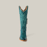 The Kellie Turquoise Leather Sole boot features a tall shaft with intricate lighter embroidery, a snip toe, and a durable leather sole, all against a neutral background.