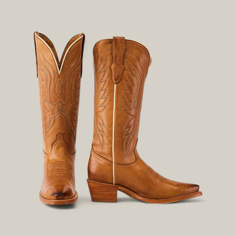 A pair of Miranda Clayton cowboy boots in brown features intricate stitching, a mid-shaft design, a snip toe, and a stacked heel with a luxurious gold leather sole. The left boot stands upright, while the right leans slightly on a neutral gray background.