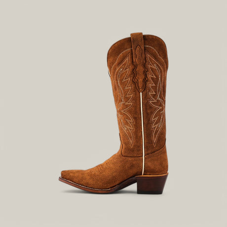 The Miranda Suede Caramel boots feature luxury craftsmanship with intricate stitching on brown suede, a snip toe, and a premium leather sole. The stacked heel of this cowboy boot is elegantly set against a plain light background.