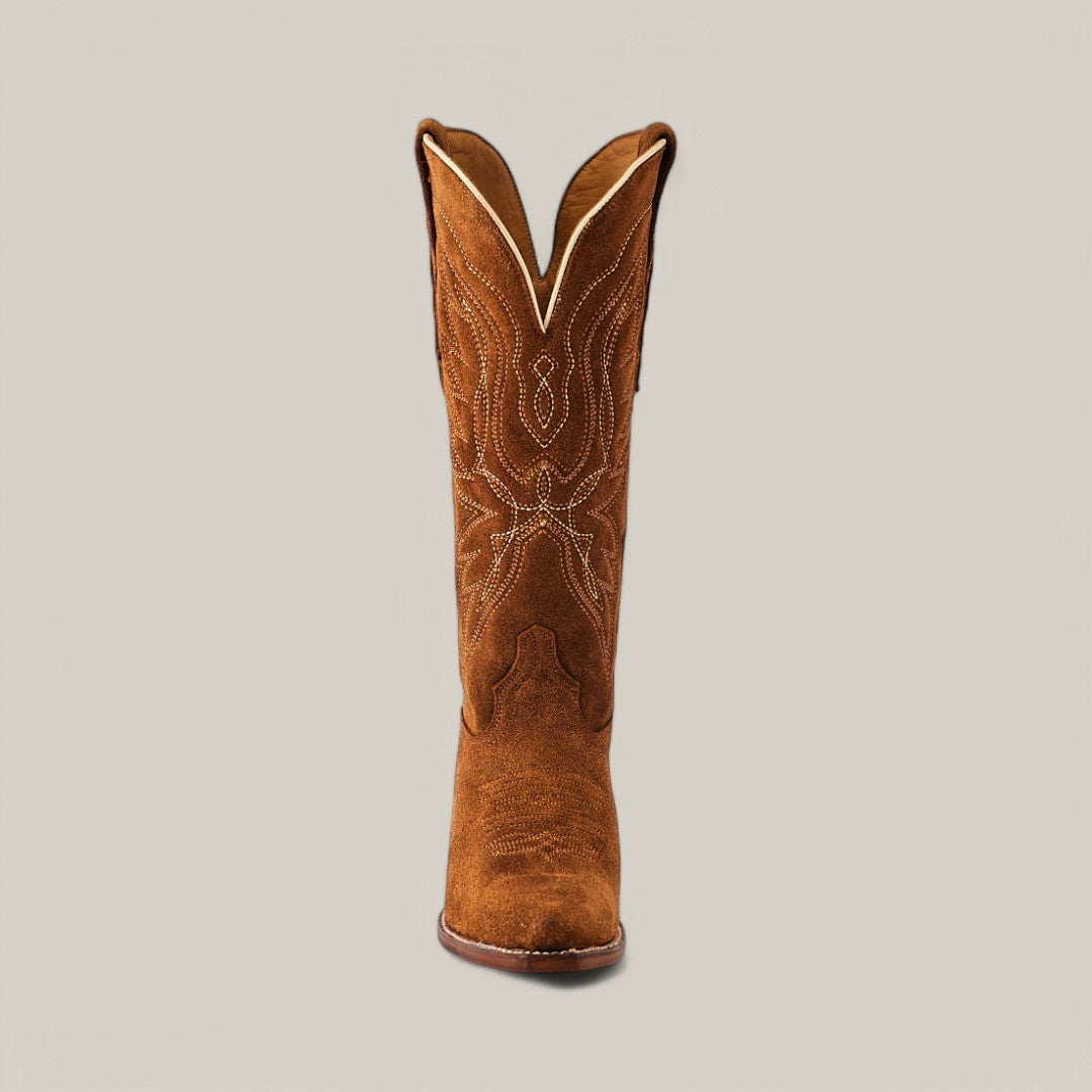 The Miranda Suede Caramel boot features a single tan design with intricate white stitching on the shaft, set against a plain grey backdrop. It has a snip toe and premium leather sole, showcasing luxury craftsmanship.