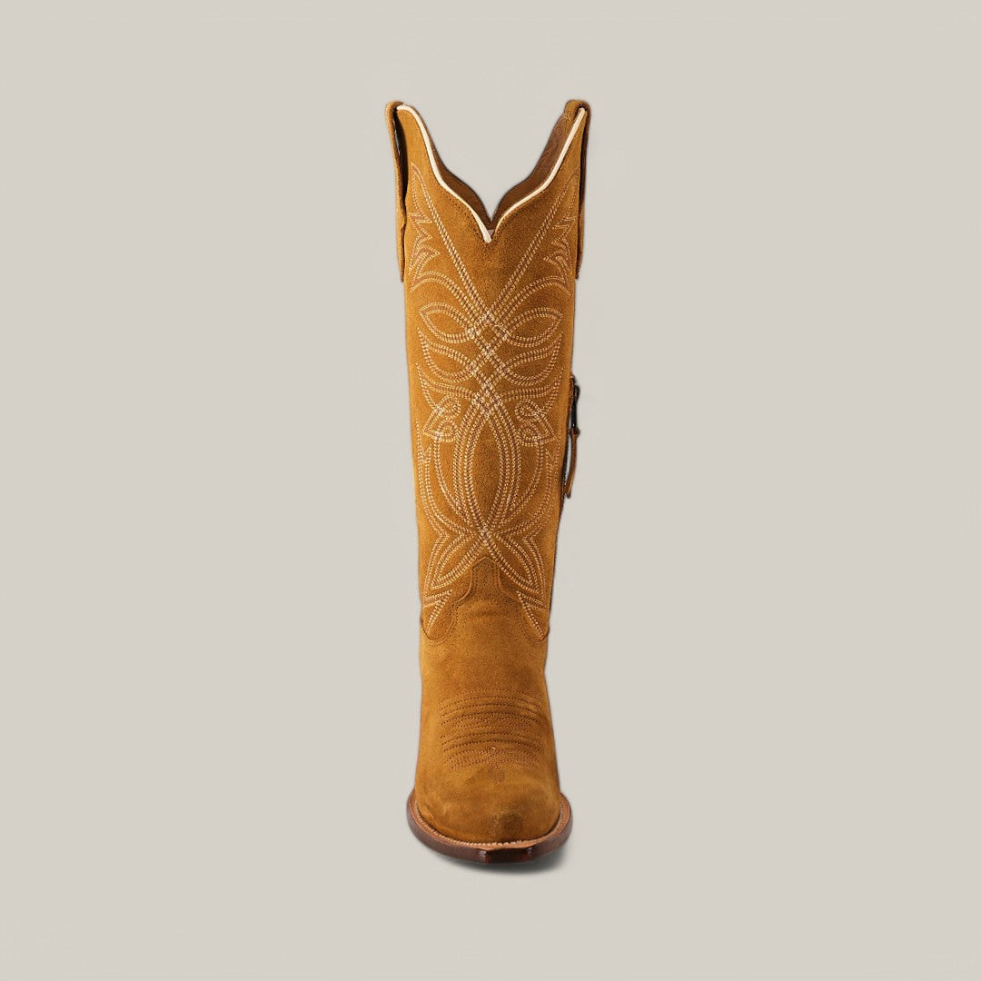 The Kellie Suede Gold Leather Sole brown cowboy boot, showcasing a tall shaft and intricate white stitching with a snip toe, stands upright against a plain light gray backdrop.