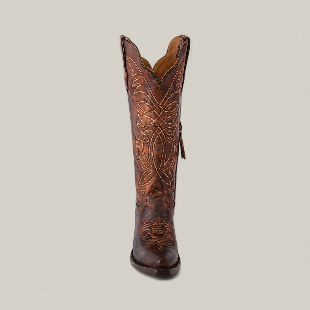 The Kellie Rustic Brown boot features a premium leather construction with intricate stitched designs on the tall shaft and snip toe, set against a plain gray background.