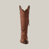 The Kellie Clayton Brown Leather Sole boot features intricate stitching on its tall shaft and snip toe, exemplifying Western elegance. This cowboy-style boot is set upright against a light gray background.