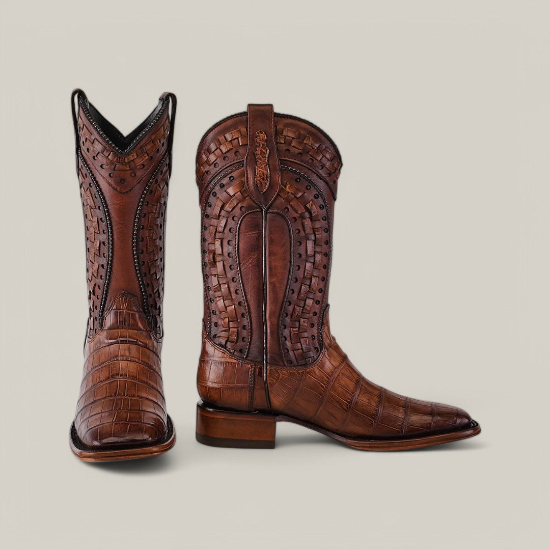 The Exotic American Alligator - Herradura boots in fawn feature luxury brown leather with a detailed basket weave pattern and intricate stitching. These Western essentials have a square toe and mid-calf shaft, reminiscent of elegant alligator boots against a neutral background.