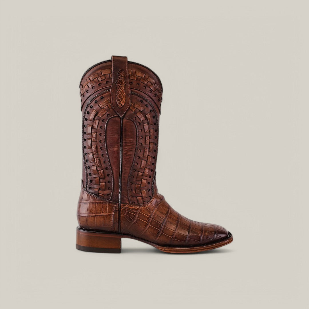 The Exotic American Alligator - Herradura boot in fawn features a textured, alligator-like pattern and intricate stitching on the shaft. Its low heel and square toe make this luxurious Western footwear stand out against a plain light gray background.