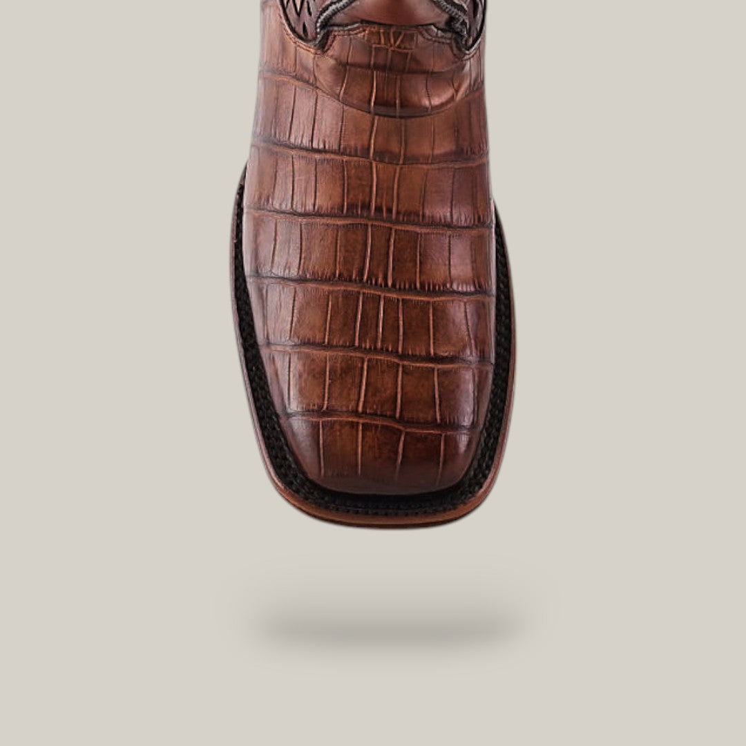 The Exotic American Alligator - Herradura - Fawn square-toe shoe, adorned with a crocodile texture pattern, is displayed against a plain background. Fine stitching outlines its design, capturing the essence of exquisite Western craftsmanship.