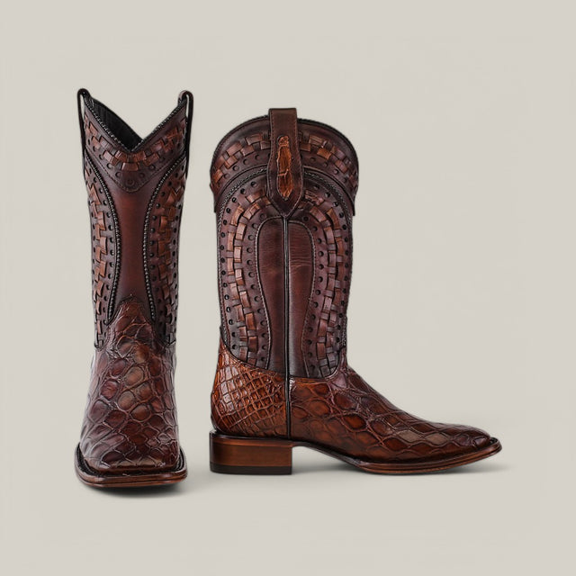 The Exotic American Alligator Herradura boots in taupe feature a square toe design with intricate woven patterns and ornate detailing on the shaft, crafted from brown leather for a stylish look.