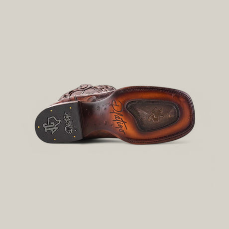 The Exotic American Alligator - Herradura - Taupe - Square Toe boot is displayed on its side, revealing its intricately engraved and branded sole. The leather boasts a rich brown hue with a glossy finish, and it features square toe detailing alongside logo and decorative stitching.