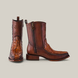 A pair of Exotic American Alligator Tail boots in fawn showcase a crocodile texture and rich brown hue. One boot stands upright, the other shows a side zipper and branded shaft logo, embodying handcrafted elegance.