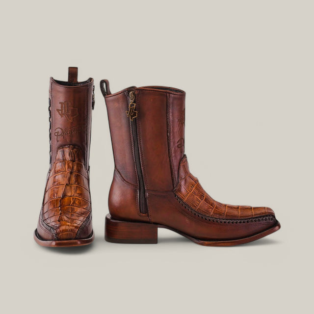 A pair of Exotic American Alligator Tail boots in fawn showcase a crocodile texture and rich brown hue. One boot stands upright, the other shows a side zipper and branded shaft logo, embodying handcrafted elegance.