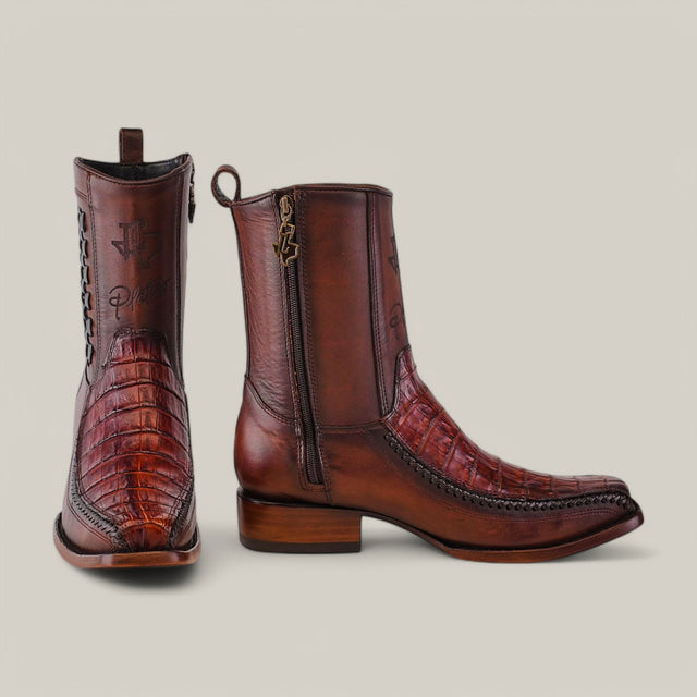 The Exotic Caiman Brandy boots feature intricate stitching on brown leather with a crocodile-like texture, western footwear charm, and visible side zippers, set against a plain light gray background.