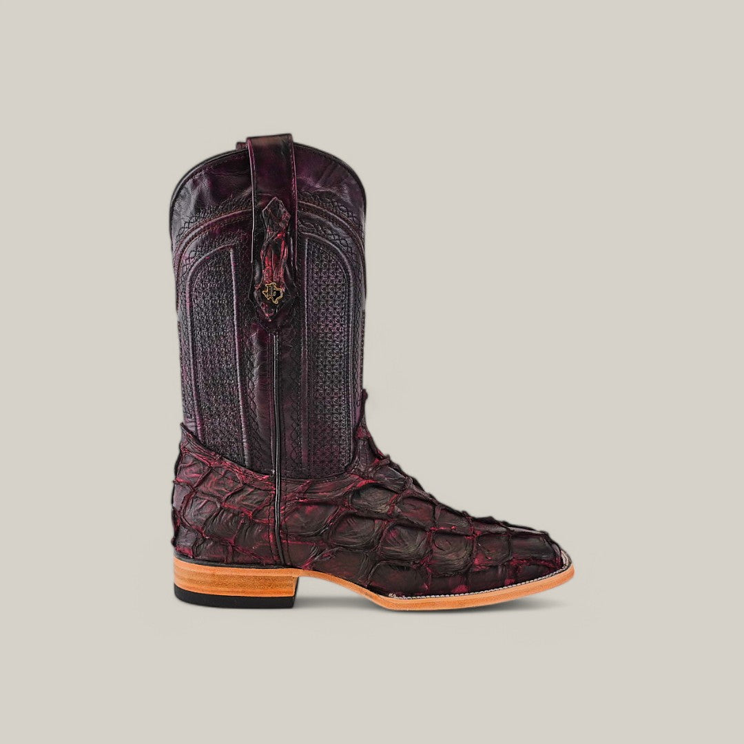 A single cowboy boot, dubbed Exotic Pirarucu Fish - Matte Black Cherry - Square Toe, showcases a textured reptile-like finish in exotic dark burgundy leather with intricate shaft stitching and a square-toe design. It rests on a light brown sole against a plain light gray background.