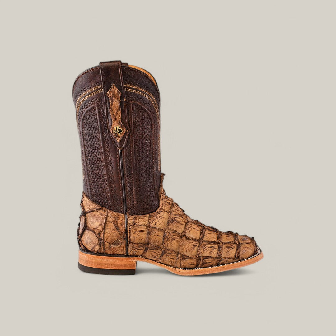 A single cowboy boot features a textured, brown and tan alligator-patterned design. It has a dark brown shaft with decorative stitching and a light brown sole. Crafted from Exotic Pirarucu Fish with a Matte Orix finish, it resembles the allure of Amazonian Pirarucu against light gray.