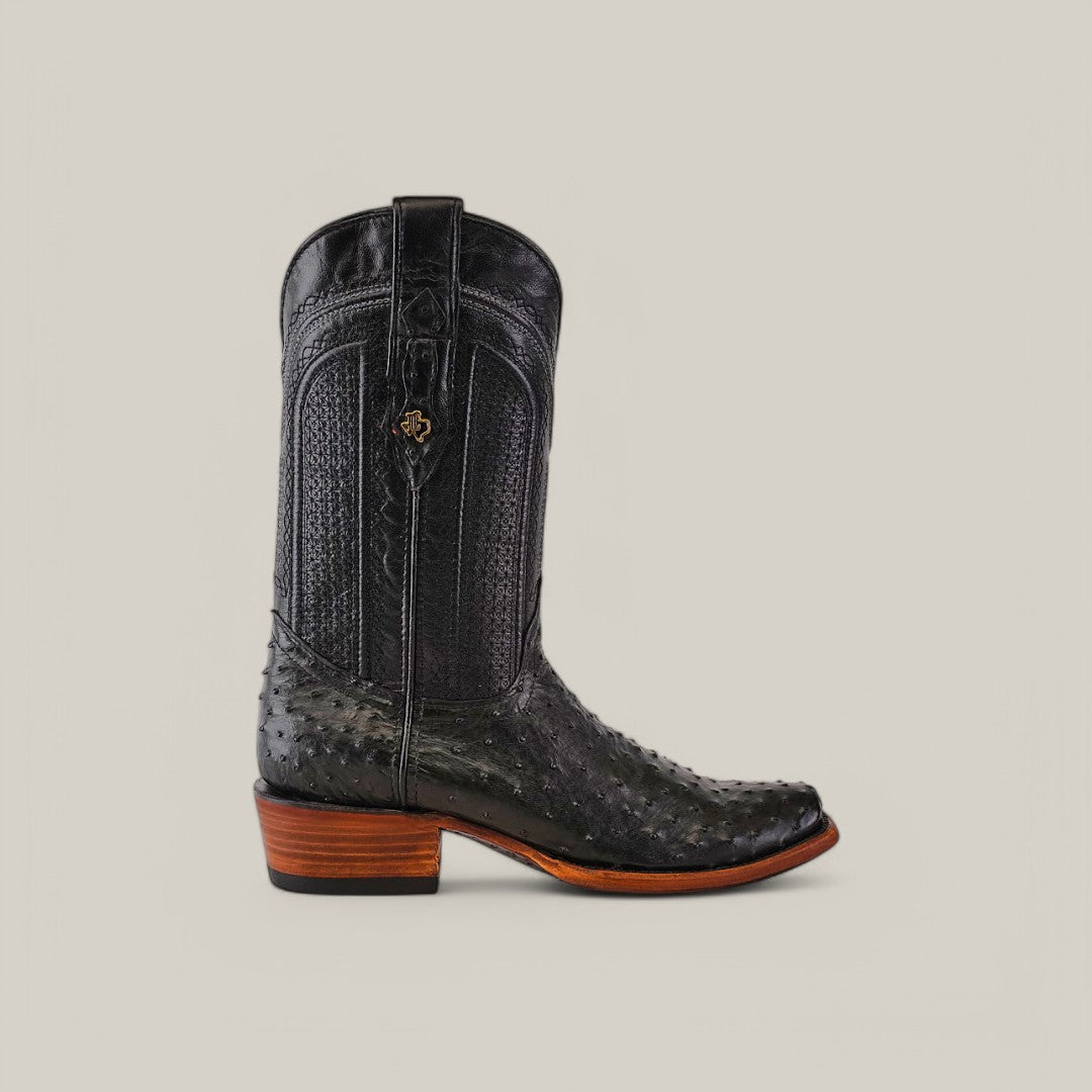 The Exotic Ostrich boot in black features genuine leather with a detailed pattern and sturdy heel, plus a Western heritage emblem. Displayed against a light gray backdrop, its narrow square toe complements the design seamlessly.