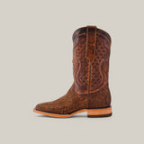 A single Exotic Python - Tamarindo cowboy boot in brown is showcased, featuring intricate shaft stitching, a textured design, a square toe, and a low wooden heel against a beige background.