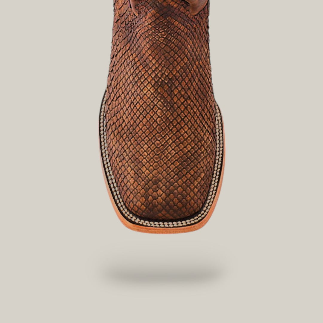 Close-up of an Exotic Python - Tamarindo boot with a scale-like pattern in brown python leather and intricate stitching on the square toe, centered against a plain light gray background.