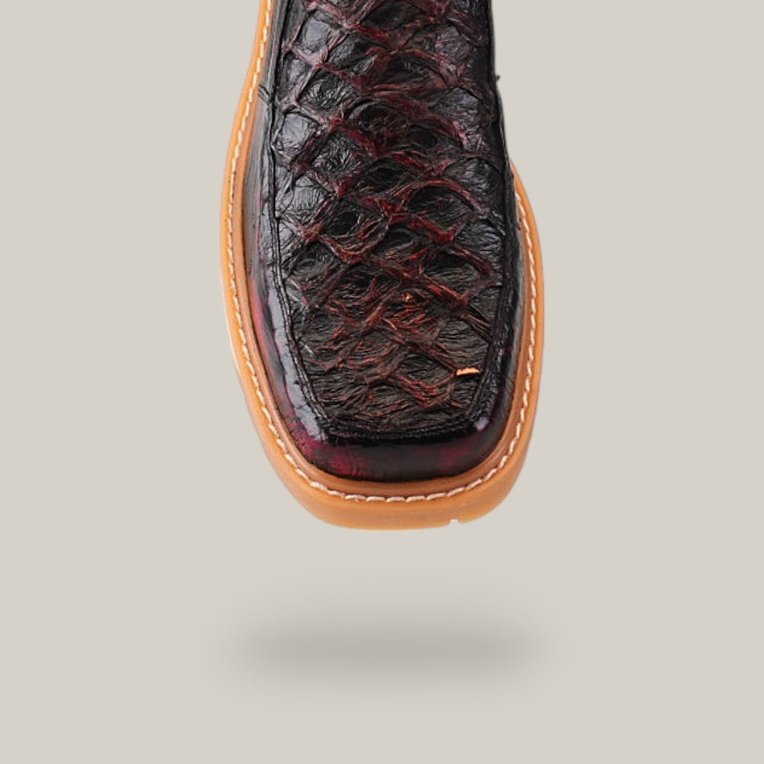 A close-up of the Exotic Pirarucu Fish Black Cherry Ankle Boot with a square toe and light brown stitched sole, shown in mid-air on a plain beige background.