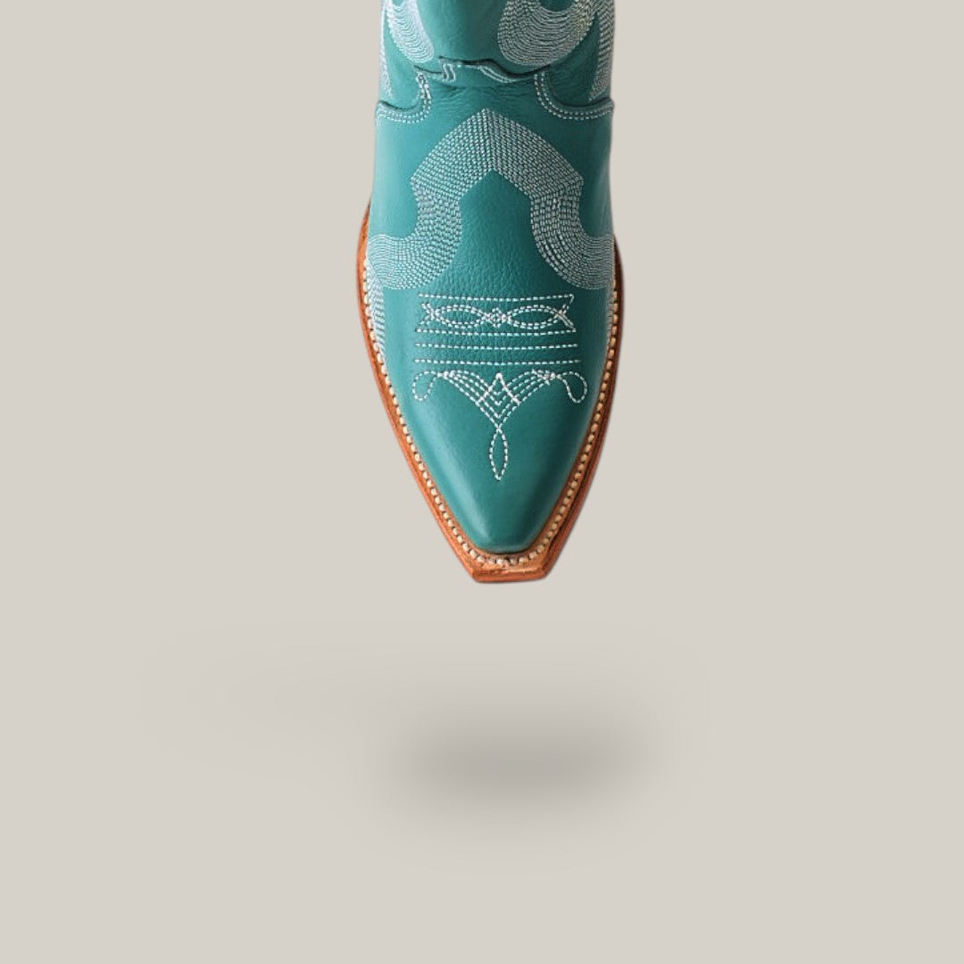 The Olimpia Green Teel cowboy boot features a tall shaft and snip toe with intricate white stitching on a brown sole, crafted from premium materials. It stands out against a plain beige background when viewed from above.