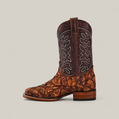 The Exotic Patchwork Pirarucu Fish - Matte Brown - Square Toe boot features a textured, patterned lower and a dark shaft with white stitching and pull straps—ideal for luxury footwear enthusiasts.