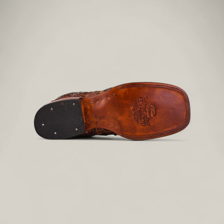 The image displays the sole of the Exotic Patchwork Pirarucu Fish - Matte Brown - Square Toe shoe, highlighting its stitched edge, square toe, metal heel tacks, and embossed logo—classic features of this luxury leather footwear.