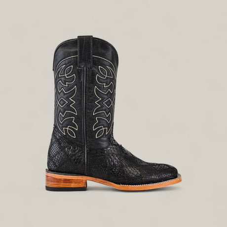 The Exotic Patchwork Python - Black - Square Toe is a luxury cowboy boot featuring decorative white shaft stitching, a snakeskin-like texture, and a tan wooden sole, all set against a plain beige background.
