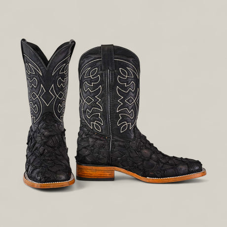 The Exotic Patchwork Pirarucu Fish - Matte Black - Square Toe boots feature black textured leather, white stitching on the shaft, eco-friendly materials, brown soles, and low heels. Displayed on a light gray background.