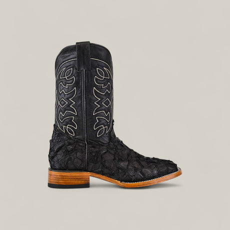 The Exotic Patchwork Pirarucu Fish - Matte Black - Square Toe boot features eco-friendly materials, a textured patterned lower, white stitching on the upper shaft, pull straps, and a brown wooden heel, set against a plain light background.