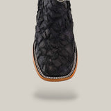 A close-up of the Exotic Patchwork Pirarucu Fish boot in matte black, featuring a square toe, eco-friendly textured fish leather, detailed stitching, and light brown and white trim, set against a plain light background.