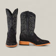 A pair of Exotic Patchwork Python cowboy boots in Matte Black, featuring a square toe and intricate white stitching, with light brown wooden heels, shown against a plain light-colored background.