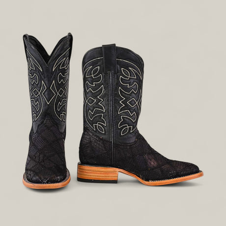 A pair of Exotic Patchwork Python cowboy boots in Matte Black, featuring a square toe and intricate white stitching, with light brown wooden heels, shown against a plain light-colored background.