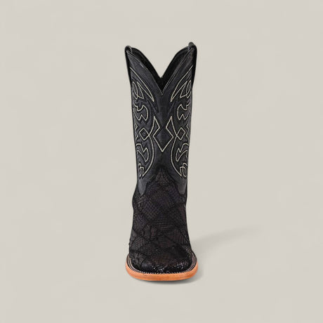 The Exotic Patchwork Python - Matte Black - Square Toe boot, featuring decorative stitching, textured patterns, and a light brown sole, stands upright against a plain light gray background.