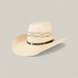 The 50x Brazil Straw Hat features a light beige color, wide brim for sun protection, decorative crown cutouts, and a black hatband with silver accents—ideal for effortless summer style against a plain background.