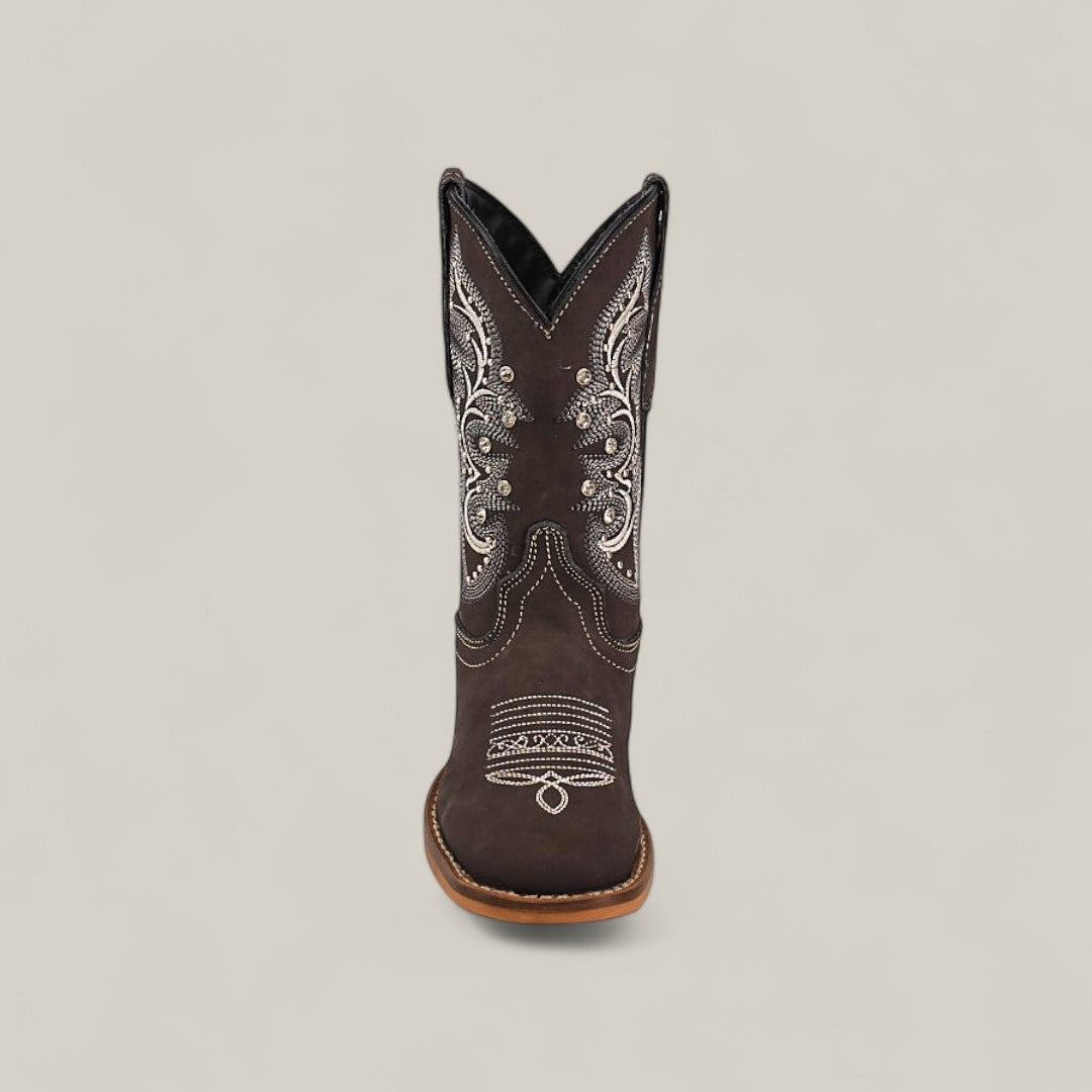 The Amara Suede Oxford - Square Toe Kids Boot, shown from the front against a plain light background, features dark brown suede with white embroidery and decorative stitching, highlighting craftsmanship found in fine square-toe shoes.