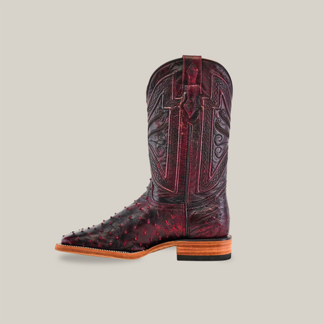 The Exotic Full Quilt Ostrich boot in black cherry, crafted from genuine ostrich leather, features intricate stitching and embossed patterns. It boasts a square toe, wooden heel, and decorative designs on the shaft against a solid light background.