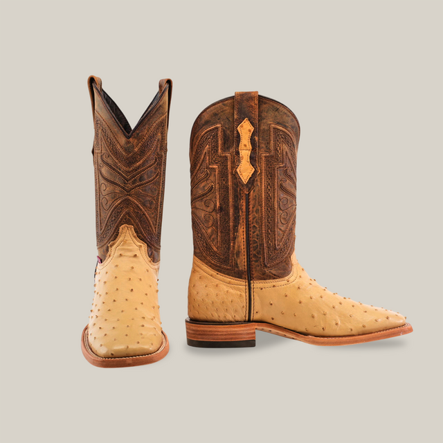 The Exotic Full Quilt Ostrich - Orix - Square Toe cowboy boots feature beige ostrich leather on the foot and dark brown, intricately stitched leather on the upper. The left boot is displayed facing forward, and the right boot is shown from a side view.