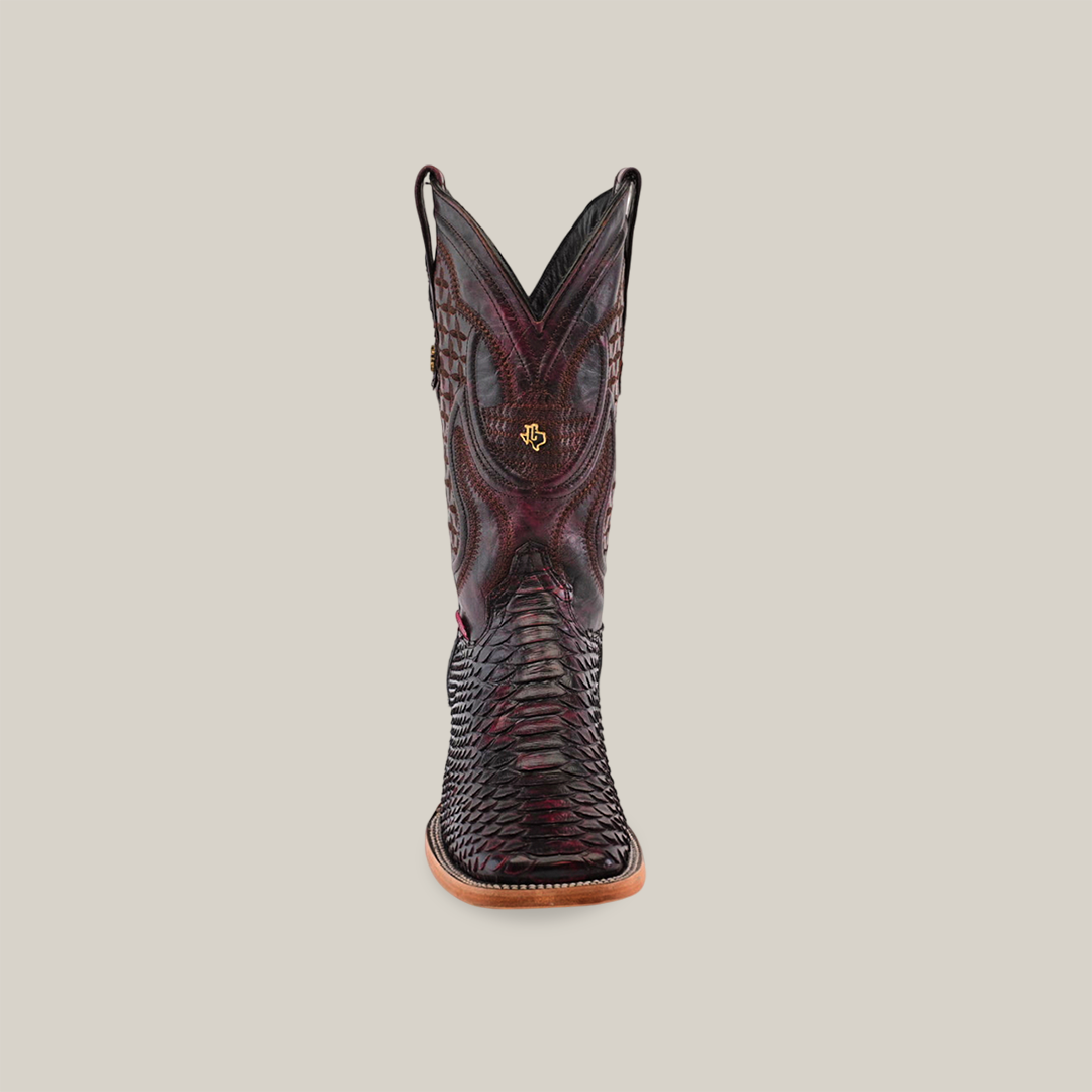 Front view of a single Exotic Python - Black Cherry boot with intricate patterns. The dark-colored boot features textural details and a small emblem near the top, a tan sole, and a square toe against a solid beige background.